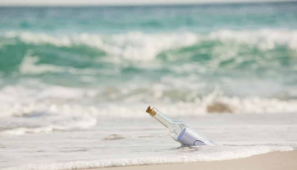 wine bottle in sand by ocean